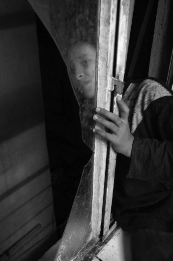 Daour Mathoob, Fatima's sister, stands in the shattered window of the family's Baghdad, Iraq apartment