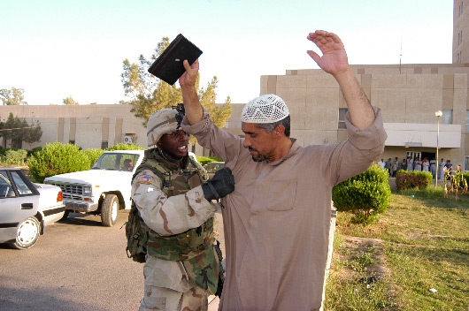 Spec. Robenson Jean searches an Iraqi after an IED attack